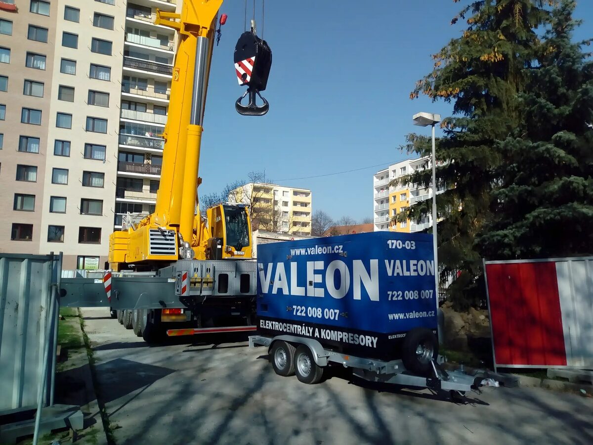 Modrá mobilní elektrocentrála Valeon na přívěsu u autojeřábu před panelovým domem