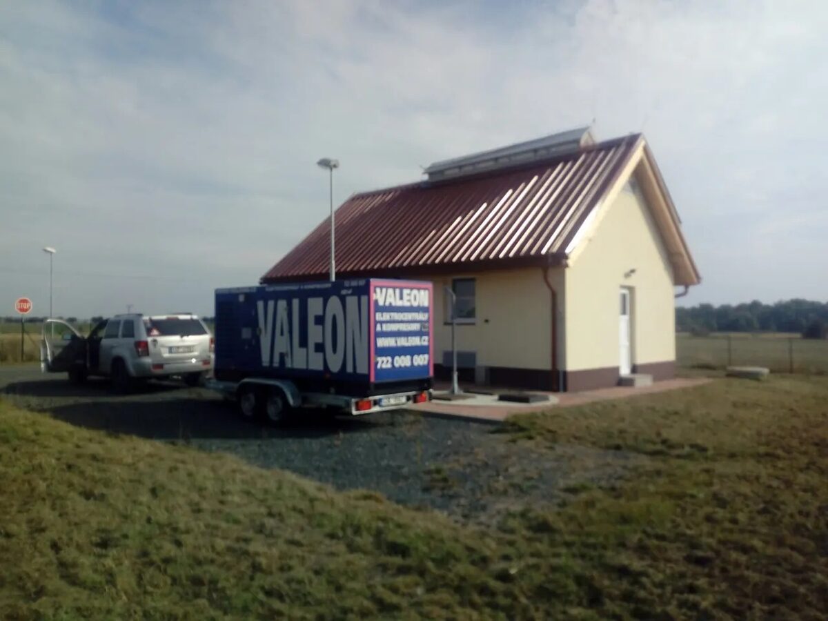 Mobilní elektrocentrála Valeon na přívěsu u malé technické budovy mezi poli
